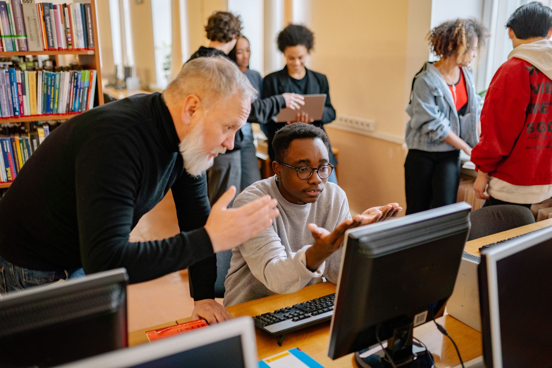Teacher supporting a student at a computer in a learning space